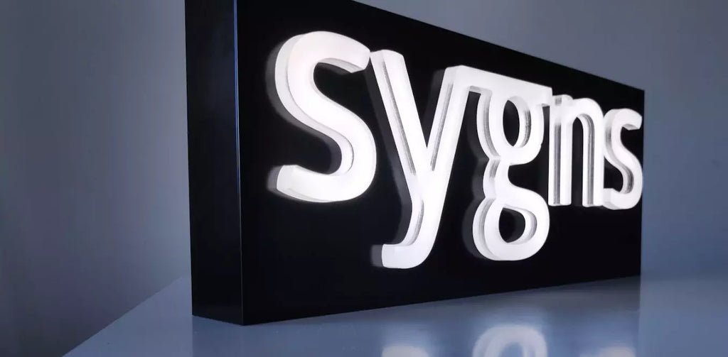 Sygns logo as white fully lit machined letters on black box standing on a desk
