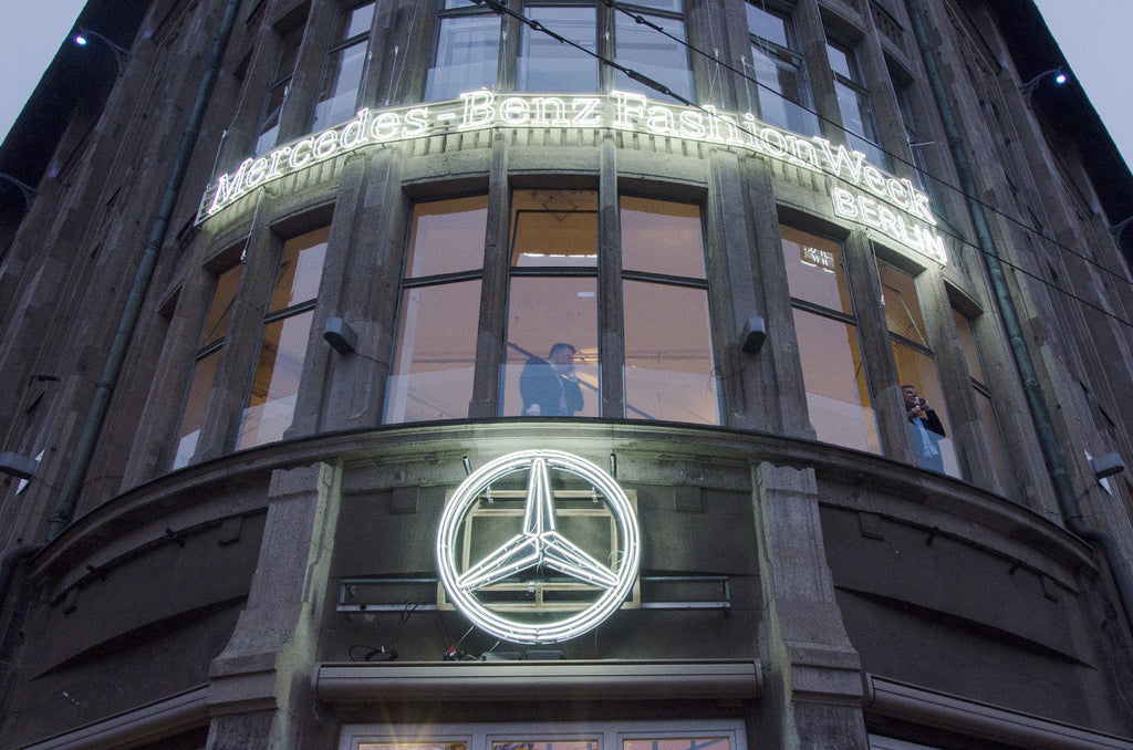 white neon signs on building facade - mercedes-benz fashion week + mercedes-benz logo